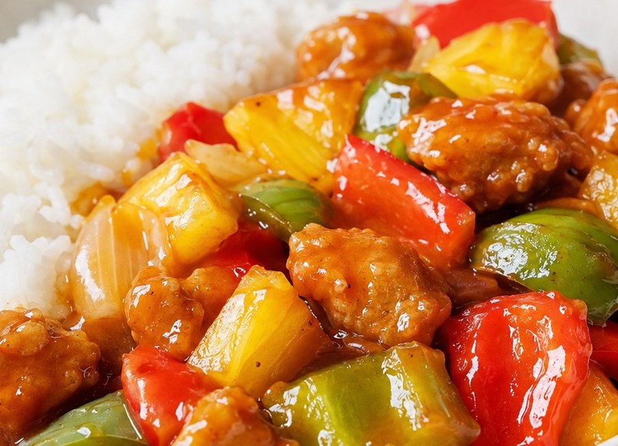 Sweet and sour chicken with peppers and pineapple served beside white rice